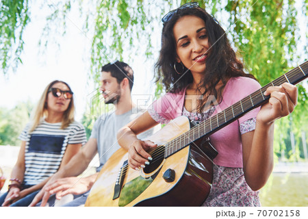 Group of happy friends with guitar. While one of them is playing guitar and others are giving him a round of applause 70702158
