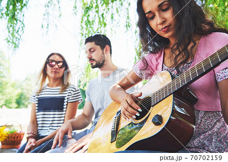 Group of happy friends with guitar. While one of them is playing guitar and others are giving him a round of applause 70702159