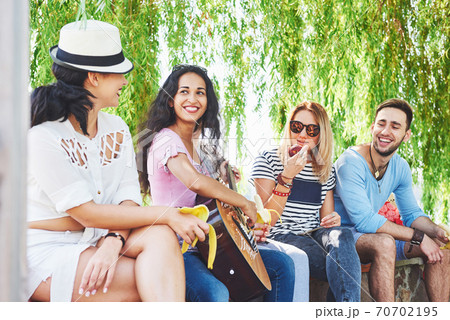 Group of happy friends with guitar. While one of them is playing guitar and others are giving him a round of applause 70702195