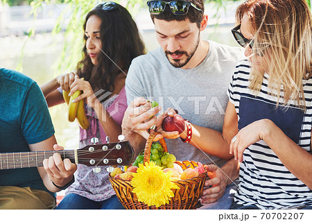 Group of happy friends with guitar. While one of them is playing guitar and others are giving him a round of applause 70702207