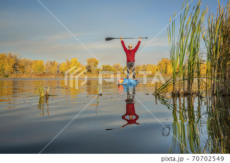 senior stand up paddler on a lake 70702549