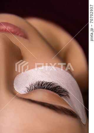 Eyelash Extension Procedure. Close up view of beautiful female eye with long eyelashes, smooth healthy skin. 70702937