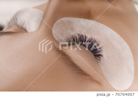 Eyelash Extension Procedure. Close up view of beautiful female eye with long eyelashes, smooth healthy skin. 70704007