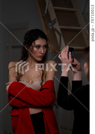 A young beautiful oriental woman with long black hair in a red jacket against a black background. The fashion model poses in the studio. 70710013