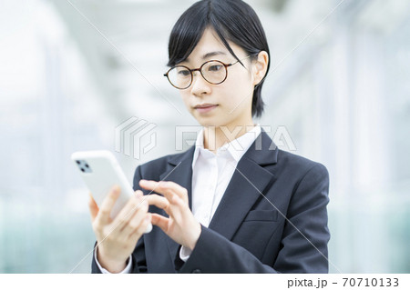スマートフォンを操作するスーツ姿の若い女性 70710133