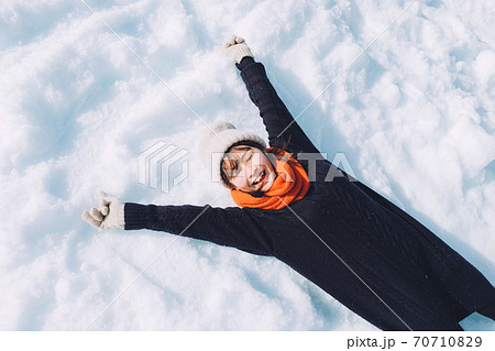 雪の上に寝転がる女の子の写真素材