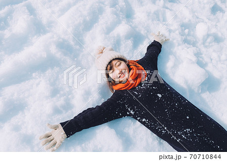 雪の上に寝転がる女の子の写真素材