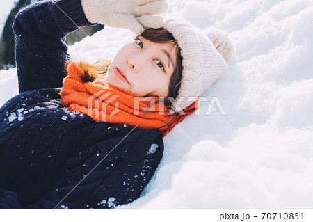 雪の上に寝転がる女の子の写真素材