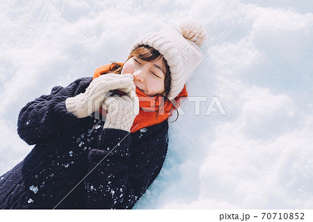 雪の上に寝転がる女の子の写真素材