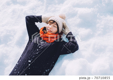 雪の上に寝転がる女の子の写真素材