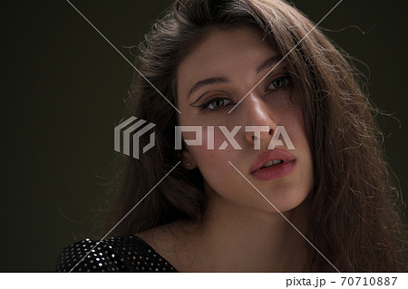 A beautiful young tall girl with long black hair poses in a shiny blouse and black culottes on a green background. Buty and fashion photo shoot. A beautiful young tall girl with long black hair poses in a shiny blouse and black culottes on a green background. Buty and fashion photo shoot. 70710887