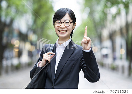 人差し指を立てるポーズをするスーツ姿の若い女性の写真素材