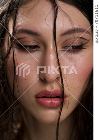 The face of a beautiful young girl with wet black hair close-up. Eastern appearance. Nude makeup, natural skin. The face of a beautiful young girl with wet black hair close-up. Eastern appearance. Nude makeup, natural skin. 70711611