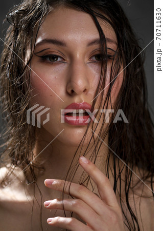 The face of a beautiful young girl with wet black hair close-up. Eastern appearance. Nude makeup, natural skin. The face of a beautiful young girl with wet black hair close-up. Eastern appearance. Nude makeup, natural skin. 70711630