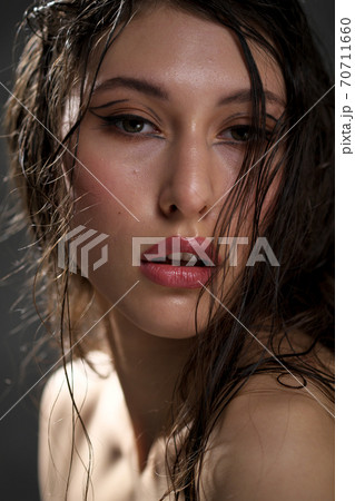 The face of a beautiful young girl with wet black hair close-up. Eastern appearance. Nude makeup, natural skin. 70711660