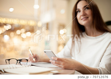 Concentrated young woman writing to do list in notepad and using task management mobile application Concentrated young woman writing to do list in notepad and using task management mobile application 70712076