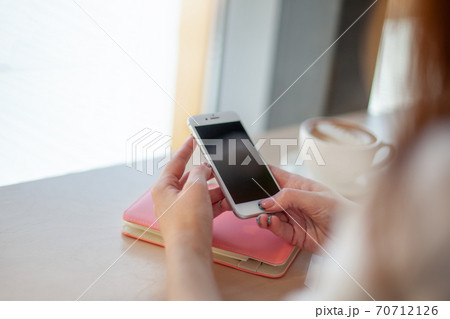 Female hands using mobile phone for organising schedule while drinking latte during the coffee break 70712126