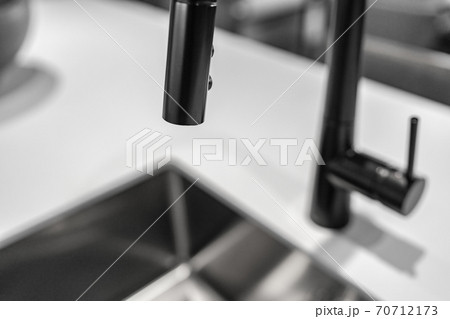 Black kitchen faucet over sink latest trend in interior design, metallic black colored metal appliances in home decor 70712173