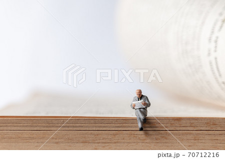 Miniature people: Businessman reading book on old book , Education or business concept. Miniature people: Businessman reading book on old book , Education or business concept. 70712216