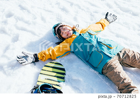 雪の上に寝転がる女の子の写真素材