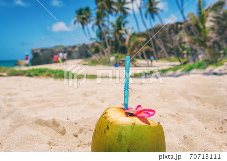 Fresh coconut water drink on beach resort holiday background with reusable eco-friendly plastic straw natural healthy food. Tropical vacation. Bottom Bay beach, Barbados, Caribbean travel 70713111