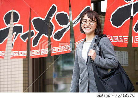 一人でラーメン店から出てくる笑顔の若い女性 70713570