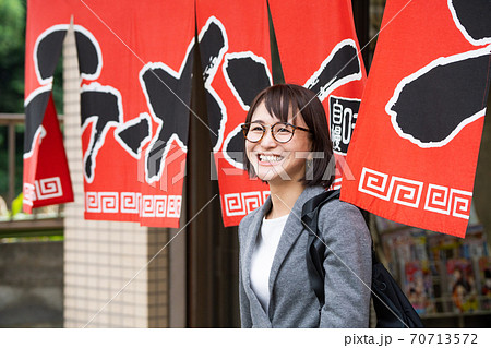 一人でラーメン店から出てくる笑顔の若い女性の写真素材