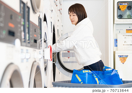 コインランドリーで洗濯する若い女性 70713644
