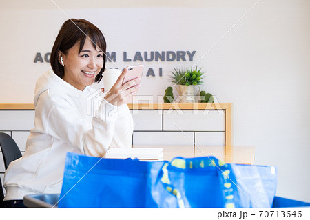 コインランドリーのカフェで待っている女性 70713646
