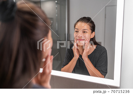 Woman washing face morning beauty skincare routing happy using soap foam in LED lighted mirror. Asian young girl massaging facewash exfoliate scrub product 70715236