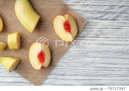 Slices of banana and peach spread on a sackcloth on a black wooden table. Cooking with a fruit diet. copy space for inscriptions 70717387
