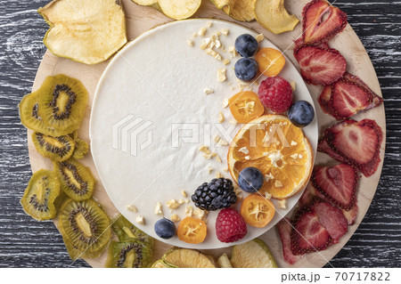Dietary delicate fruity berry nut cake without baking. Wooden stand on a black table. The concept of a useful dessert. Home cooking. The concept is not harmful sweets Dietary delicate fruity berry nut cake without baking. Wooden stand on a black table. The concept of a useful dessert. Home cooking. The concept is not harmful sweets 70717822