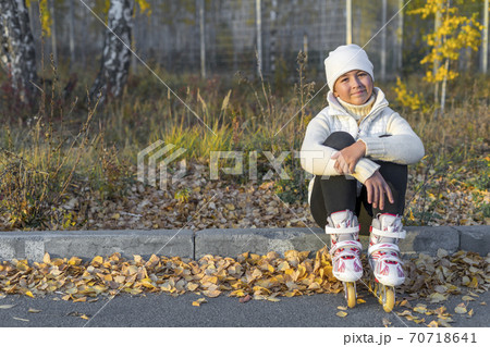 Young caucasian girl in roller blades resting sitting on concrete curb. Space for text. 70718641