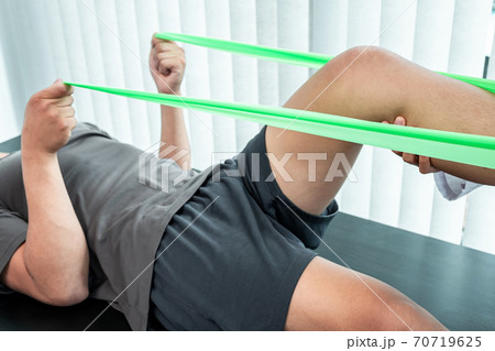 Female Physiotherapist working examining treating injured leg of patient, Doing exercises the Rehabilitation therapy pain his in clinic Female Physiotherapist working examining treating injured leg of patient, Doing exercises the Rehabilitation therapy pain his in clinic 70719625