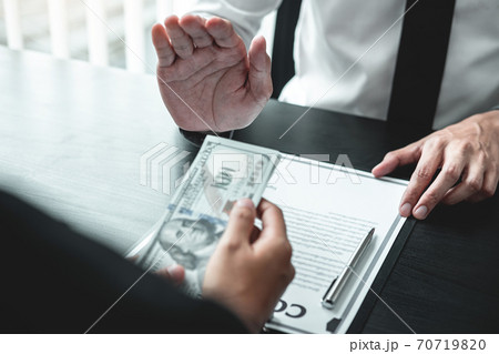 Businessman refusing receive bribe money in the envelope of their partner to give success the deal contract in a corruption scam, illegal and dishonest 70719820