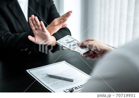 Business woman refusing receive bribe money in the envelope of their partner to give success the deal contract in a corruption scam, illegal and dishonest 70719931