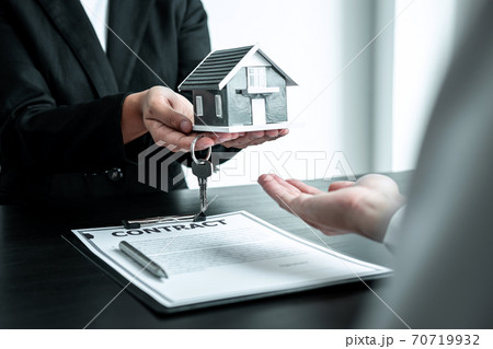 Sale Estate agent giving house model and key to new client after signing agreement contract with approved property form, Home Insurance and Real estate investment concept 70719932