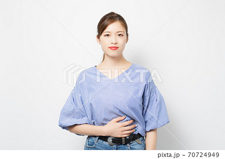 お腹に手を当てる若い女性 70724949