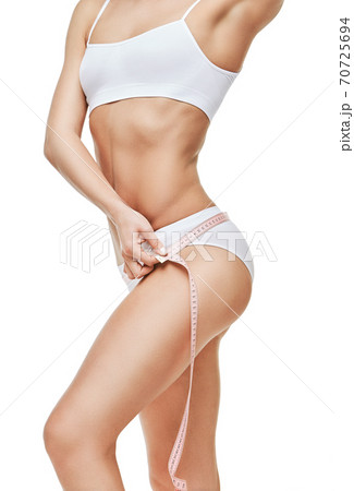Slim tanned woman's body isolated on white background - waist measurement 70725694