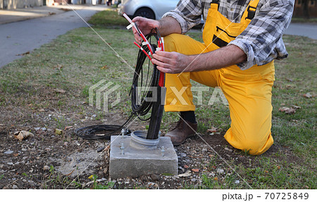 Worker and fiber optic cable lines installation at street 70725849