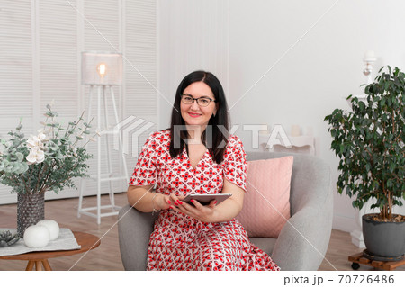 A professional doctor psychologist with glasses sits in a bright office with a tablet in his hands and smiles at the camera. Psychotherapy. Woman psychotherapist 70726486