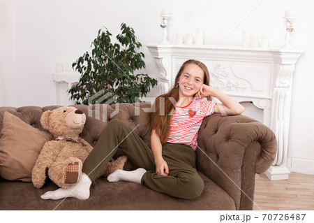 Portrait of a beautiful redhead teen girl. Cute girl sitting on the sofa, smiling and looking at the camera Portrait of a beautiful redhead teen girl. Cute girl sitting on the sofa, smiling and looking at the camera 70726487