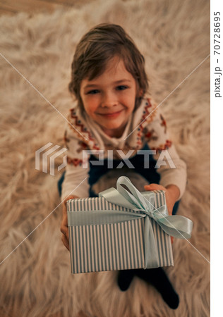 The cute boy with a gift box sitting on the floor The cute boy with a gift box sitting on the floor 70728695
