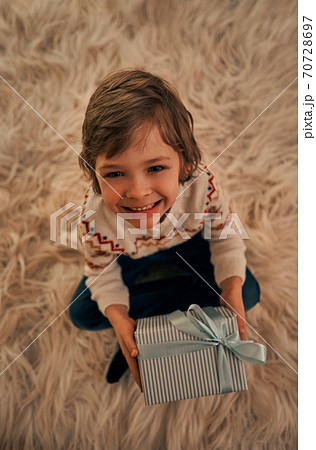The cute boy with a gift box sitting on the floor The cute boy with a gift box sitting on the floor 70728697
