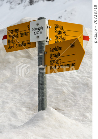 Trail sign with various hiking destinations on the Schwaegalp in snow, Switzerland 70728719