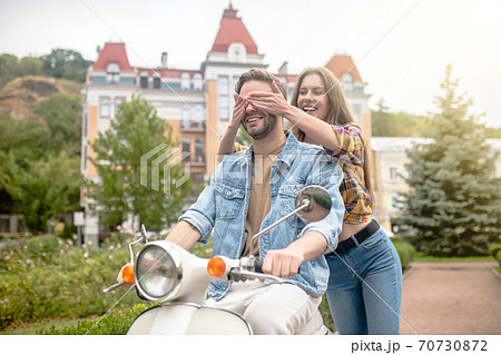 Woman closing eyes to man riding a scooter Woman closing eyes to man riding a scooter 70730872