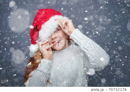 happy red-haired teenage girl in a Santa hat. photo session in the Studio with simulated snowfall happy red-haired teenage girl in a Santa hat. photo session in the Studio with simulated snowfall 70732176