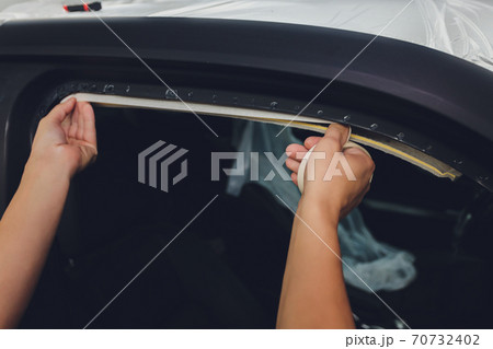 Mechanic preparing a car for painting by protecting the edges. 70732402