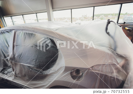 A broken car color silver, wrapped in a plastic coating. The car is covered with polyethylene after the accident. It is very debt. A broken car color silver, wrapped in a plastic coating. The car is covered with polyethylene after the accident. It is very debt. 70732555