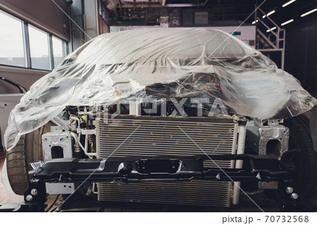 A broken car color silver, wrapped in a plastic coating. The car is covered with polyethylene after the accident. It is very debt. 70732568